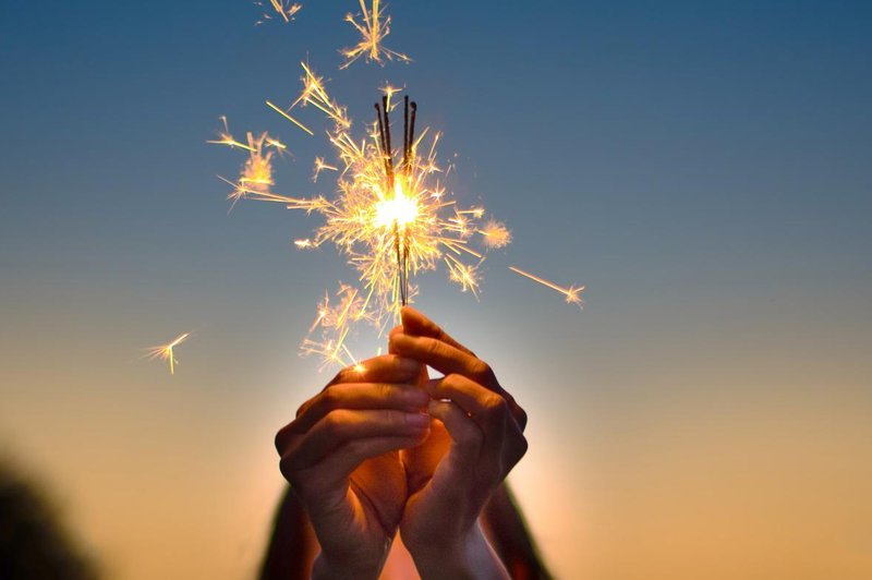 Abstract blur sparklers for celebration background,Motion by wind blurred woman hand holding burning Christmas sparkle on nature and twillight sky background.Winter vintage film grain filter style. (foto: Pk Studio Shutterstock)