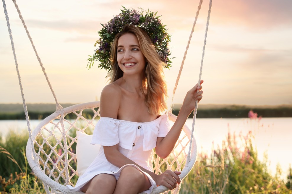 ženska s cvetličnim venčkom v laseh se guga na gugalnici v beli obleki (foto: shutterstock)